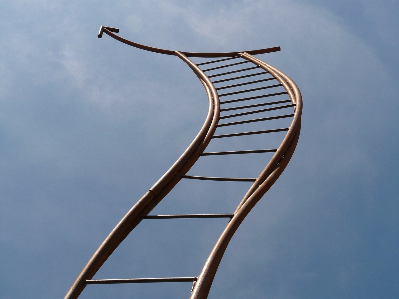 A house painter standing on a ladder beside a freshly painted wall.