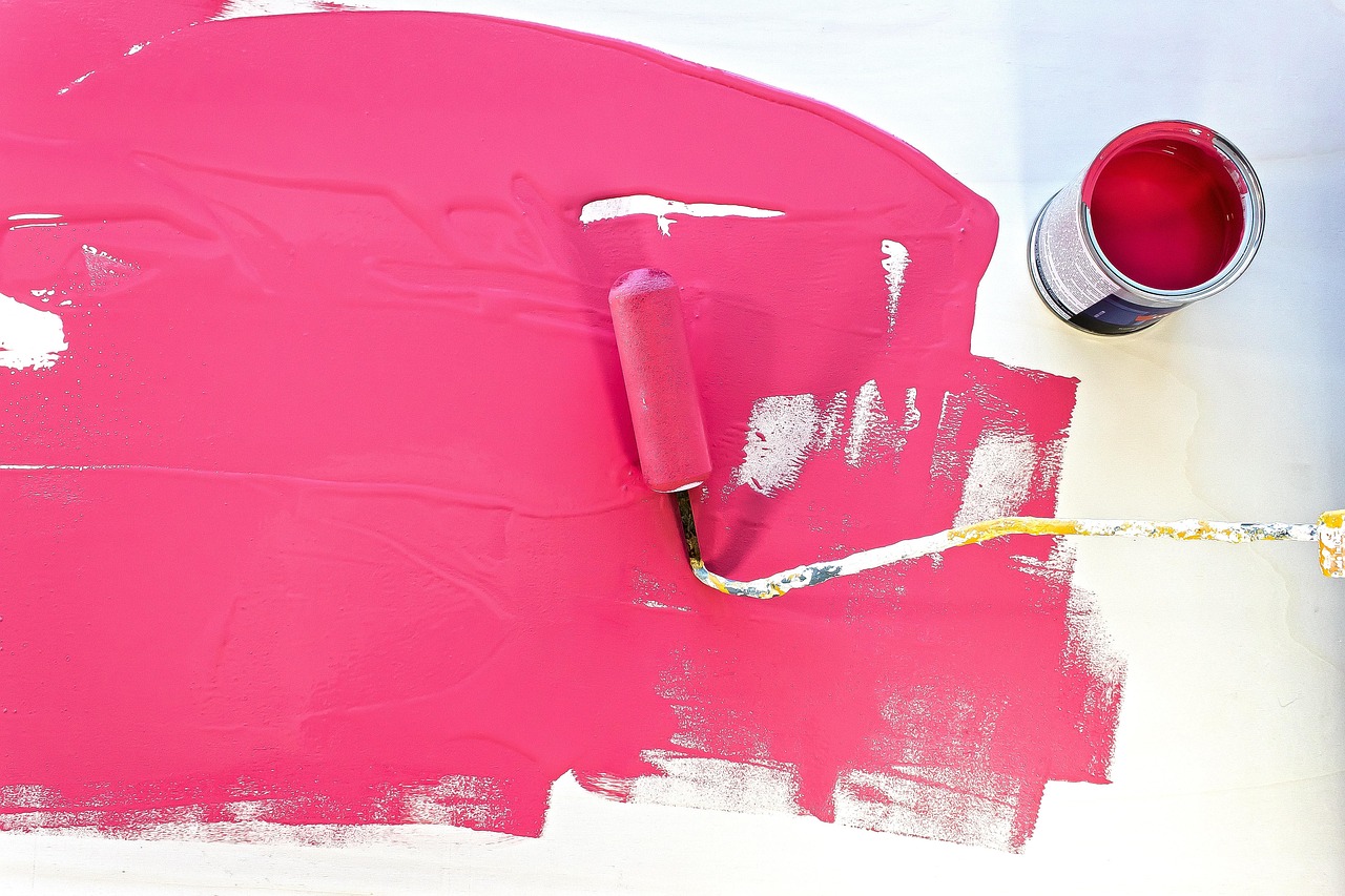 Several open paint cans with brushes and a roller resting on a drop cloth.